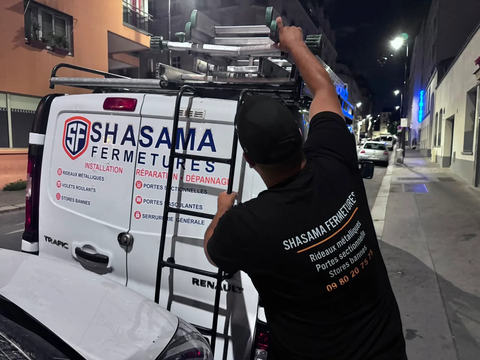 Technicien Shasama Fermetures chargeant une échelle sur le véhicule d’intervention, rue parisienne de nuit