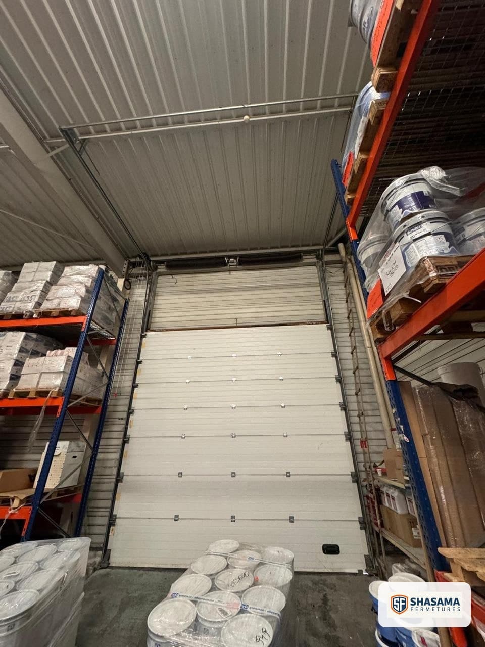 Porte sectionnelle industrielle fermée dans la zone de stockage avant la motorisation